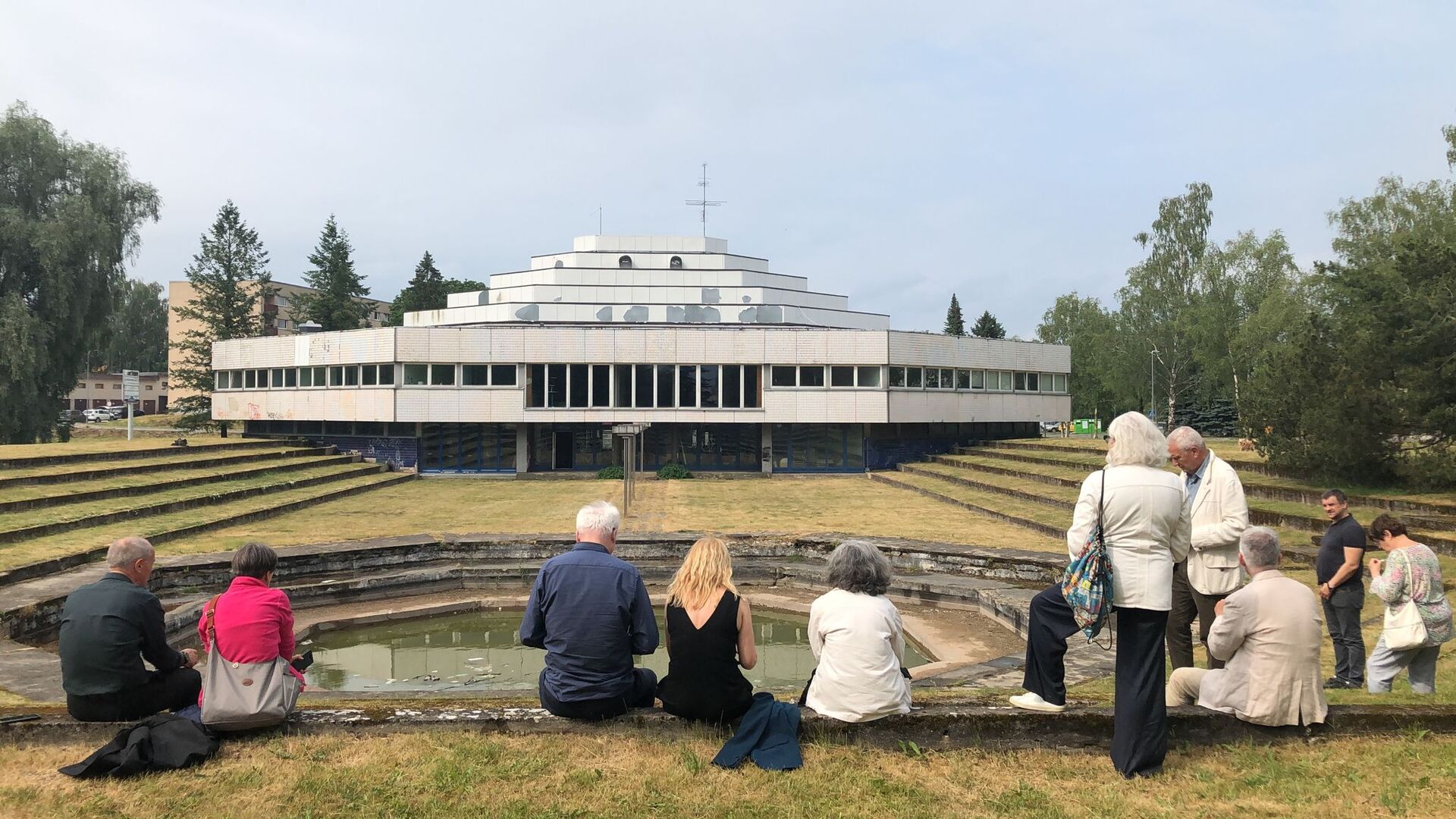 Personnes assises face à un bâtiment en arrière-plan. 