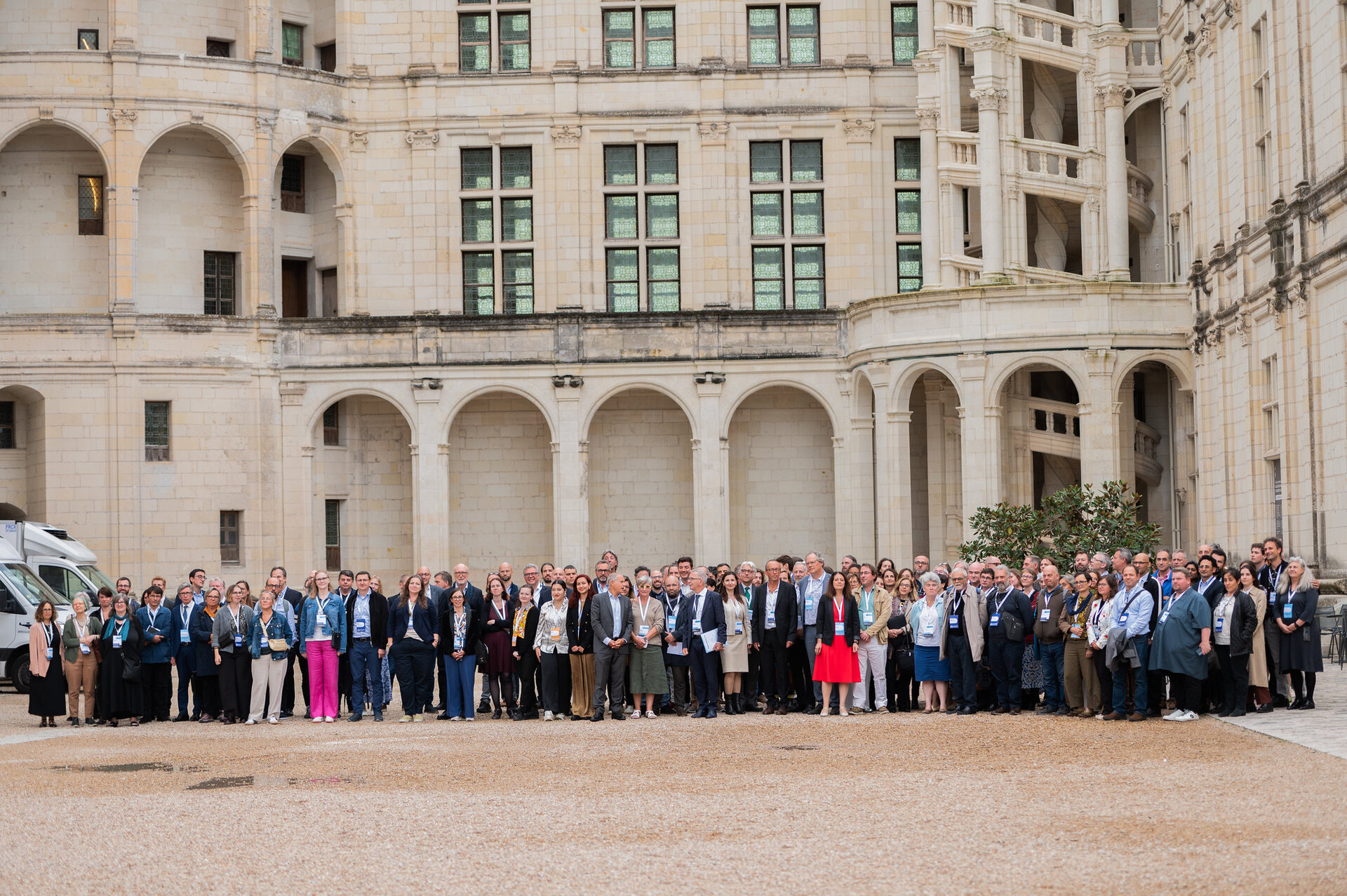 A group of more than 50 men and women posing in the inner courtyard of the Chambord Castle, France