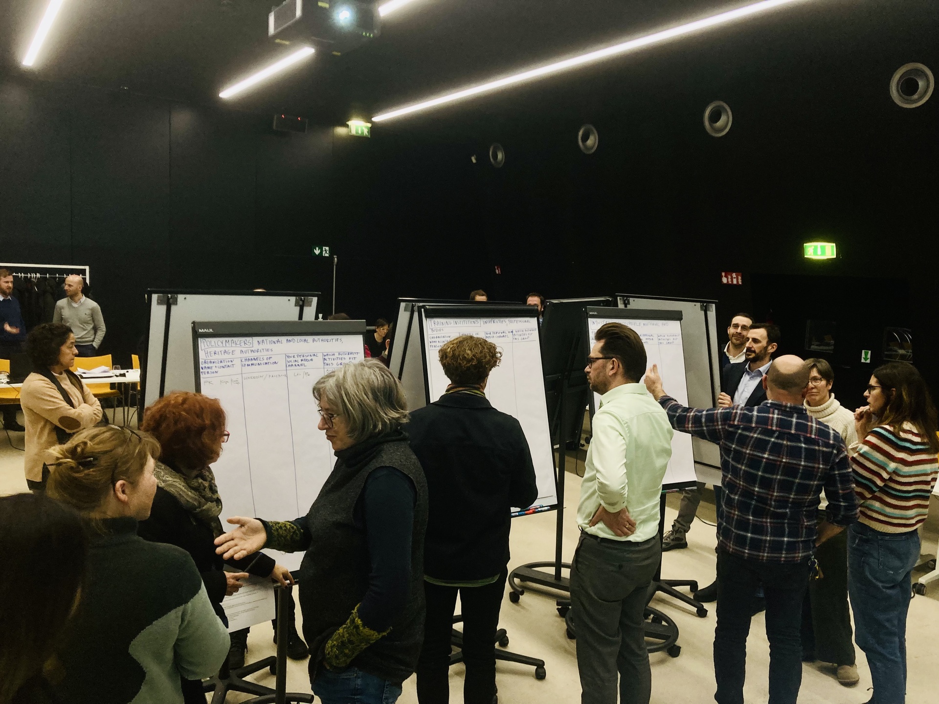 Groupe de professionnels du patrimoine partageant leurs connaissances sur des tableaux blancs.