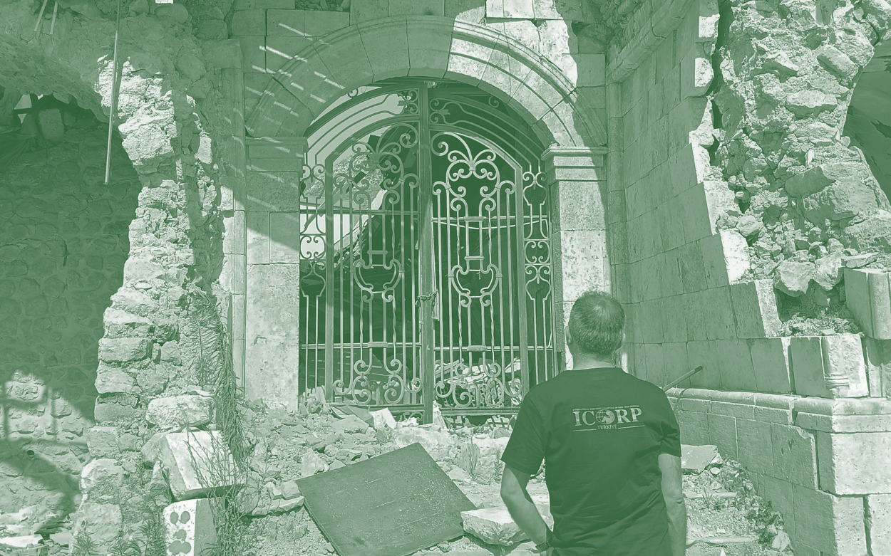 An ICOMOS ICORP member stands in front of a damaged cultural heritage building in Türkiye