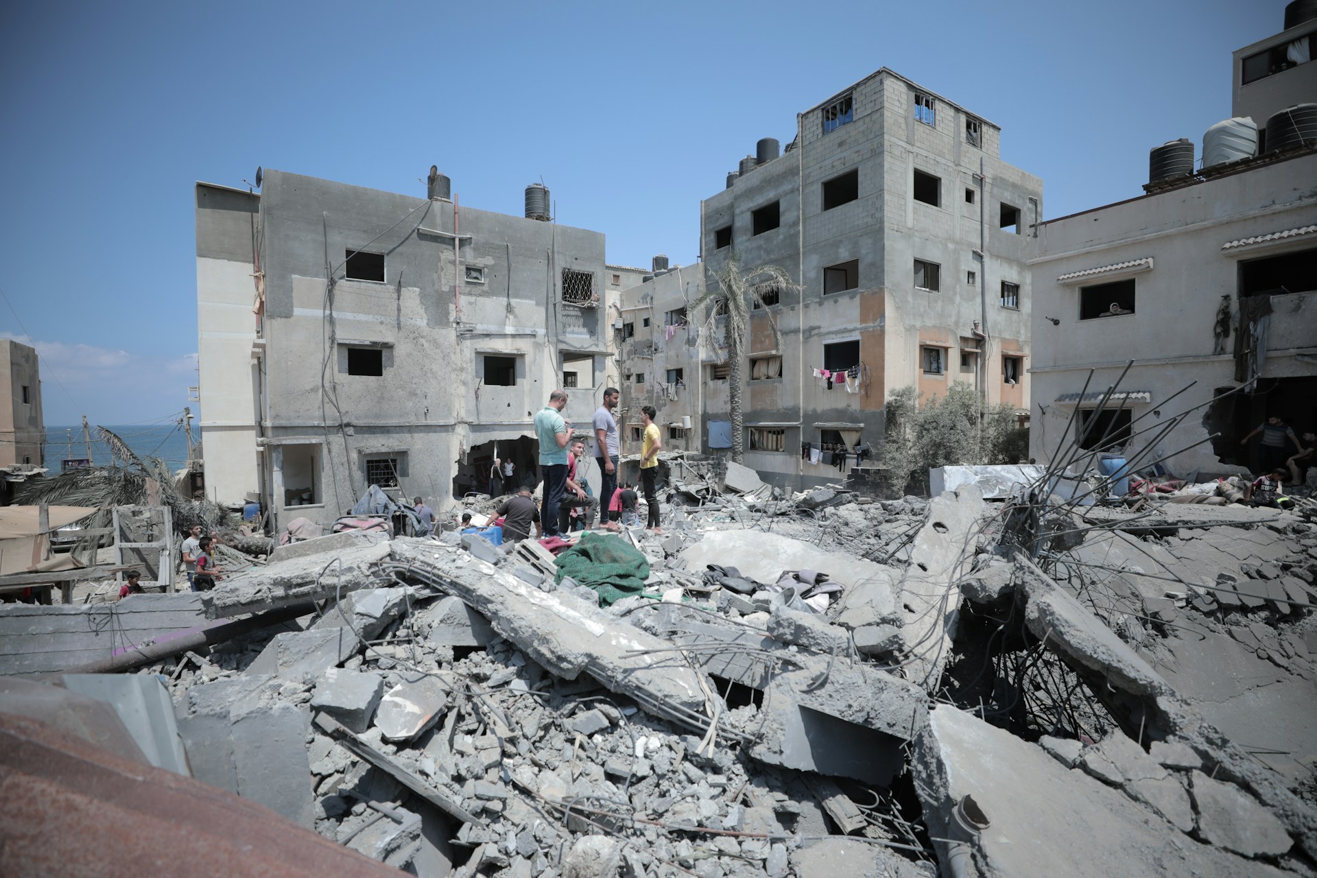 Men and children standing among ruins of buildings - ICOMOS Statement on Gaza and the West Bank
