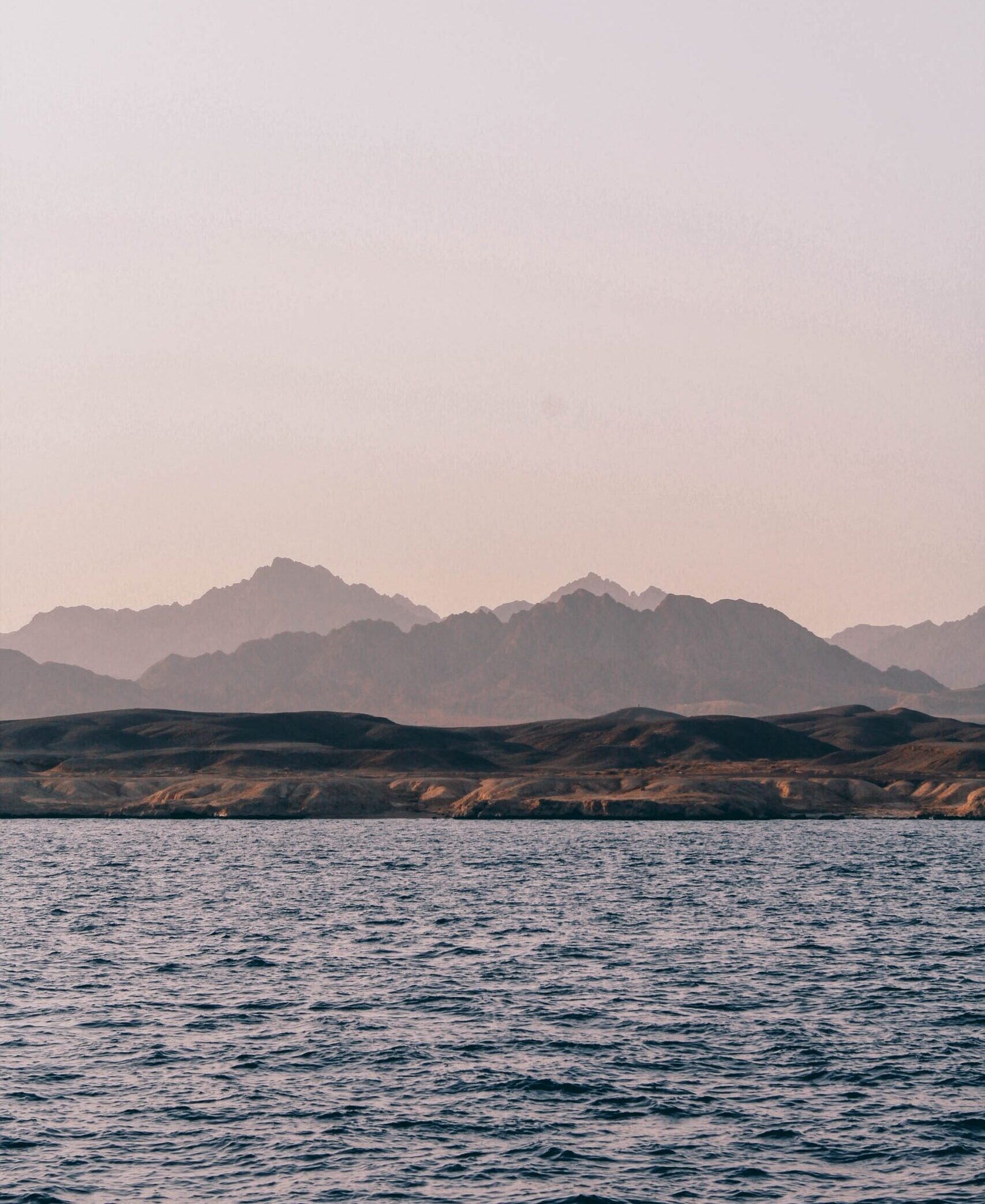 Photo d'un paysage avec la mer au premier plan et des montagnes à l'arrière plan.