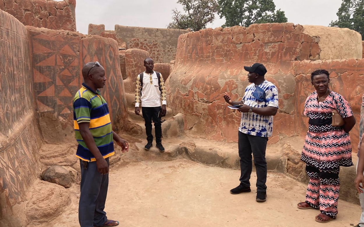 Picture showing 4 heritage professionals from Burkina Faso gathered within the Royal Court of Tiébélé compounds and evaluating the space for training purposes.